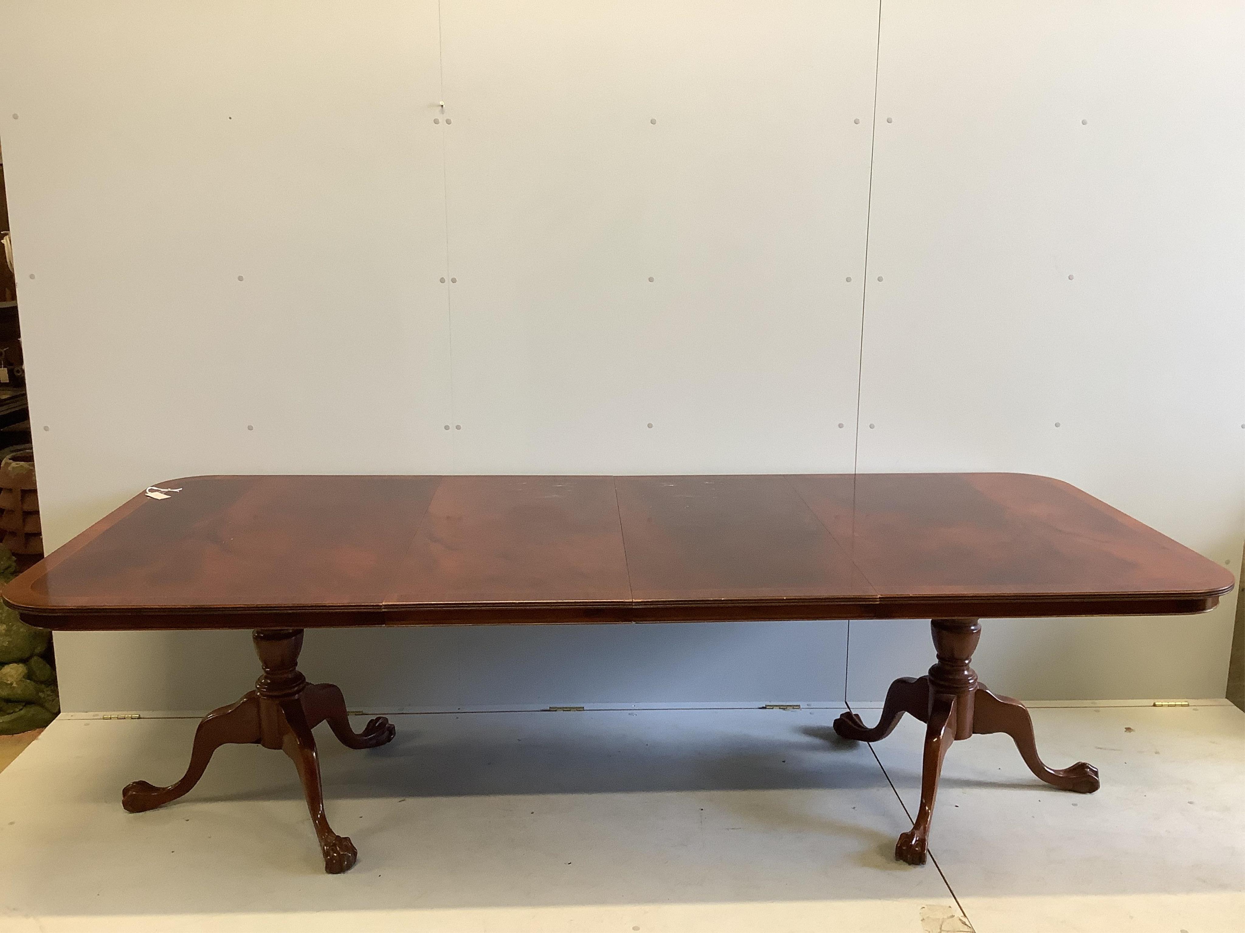 A Georgian style banded mahogany extending dining table, raised on twin turned supports and quadruple reeded splayed legs with brass castors (two additional leaves), 260cm extended, width 110cm, height 74cm, together wit